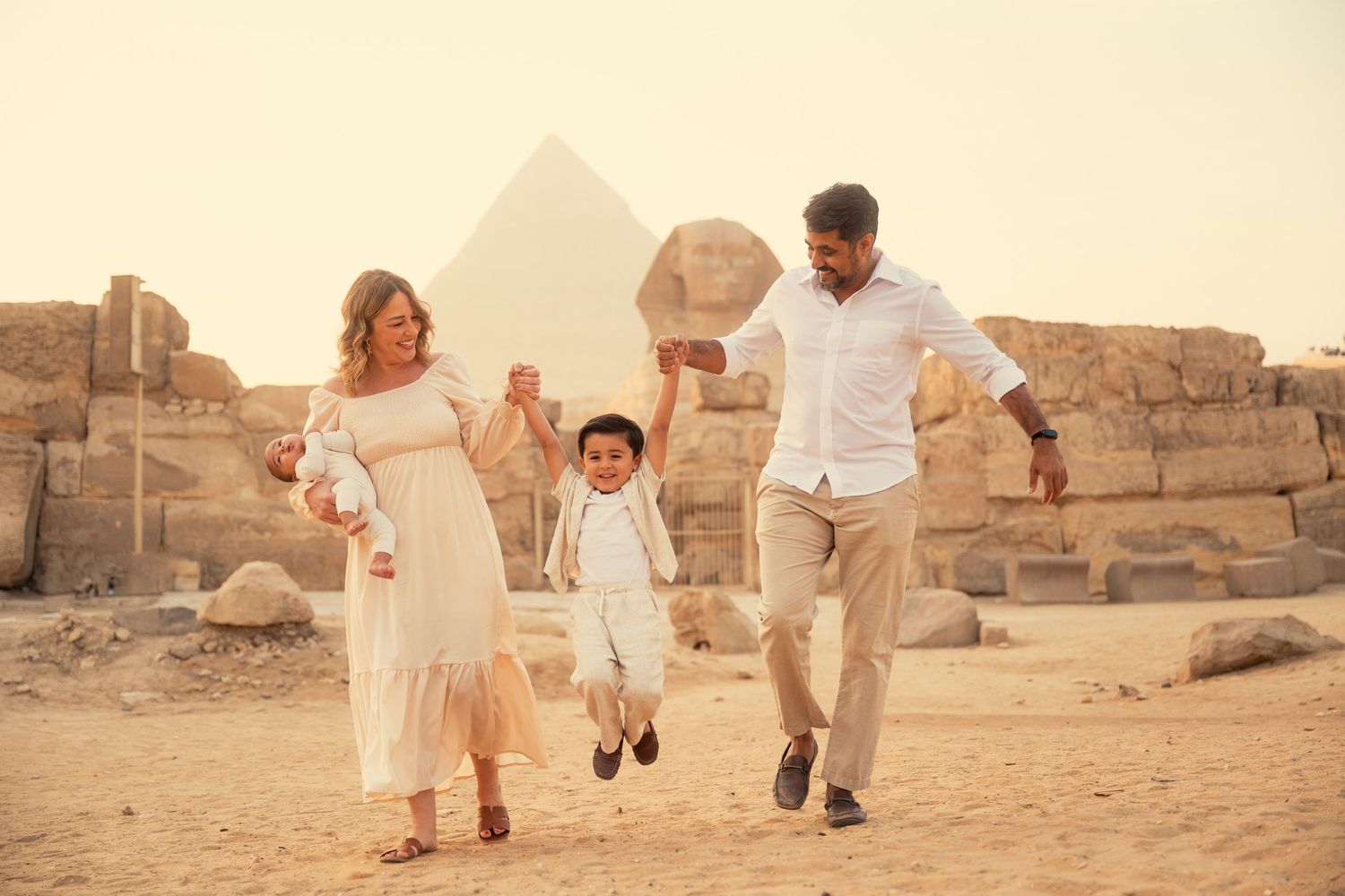 A family enjoys a joyful moment together while visiting the ancient pyramids and sphinx in Giza, Egypt.