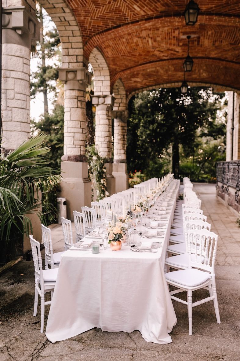 Long wedding dinner table under villa portico overlooking Lake Iseo