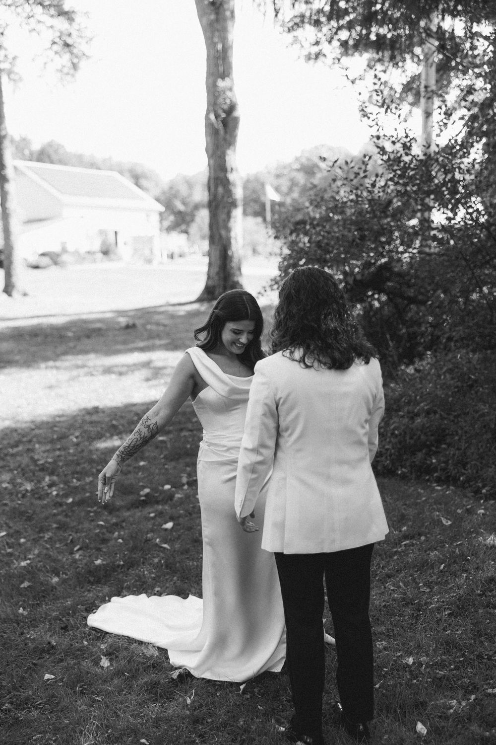 Two people walking together in a park with trees in the background, shown in black and white.