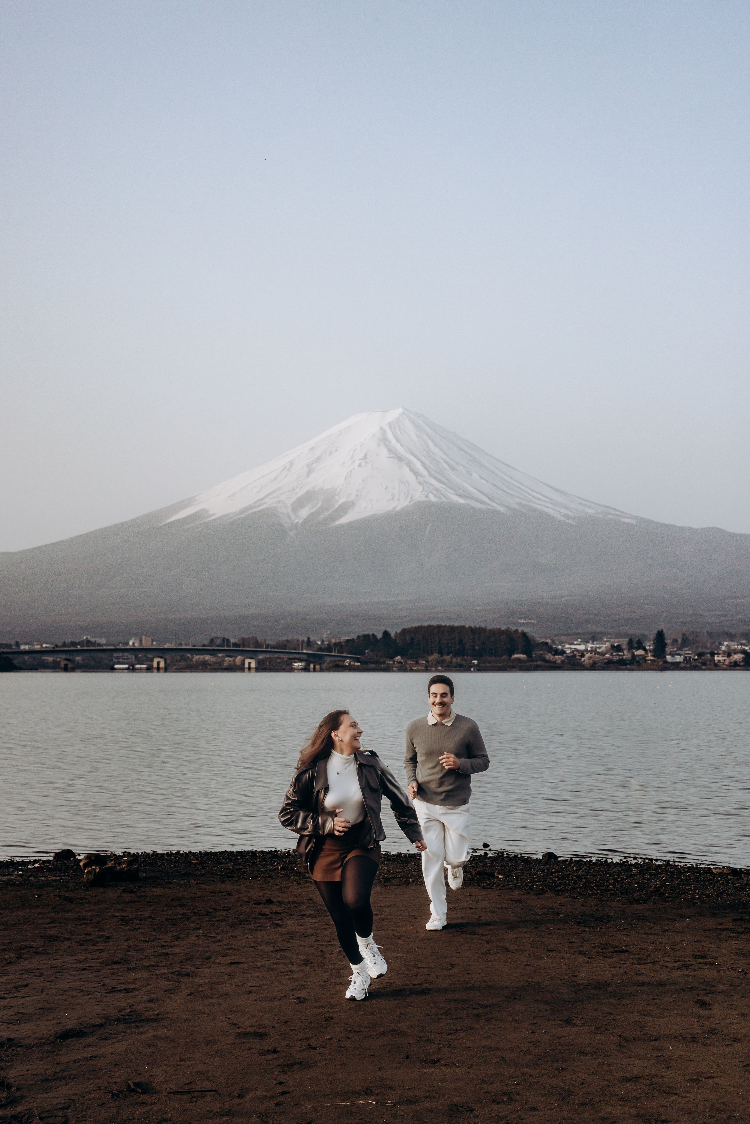 People practicing martial arts moves against the backdrop of snow-capped Mount Fuji and Lake Kawaguchiko.