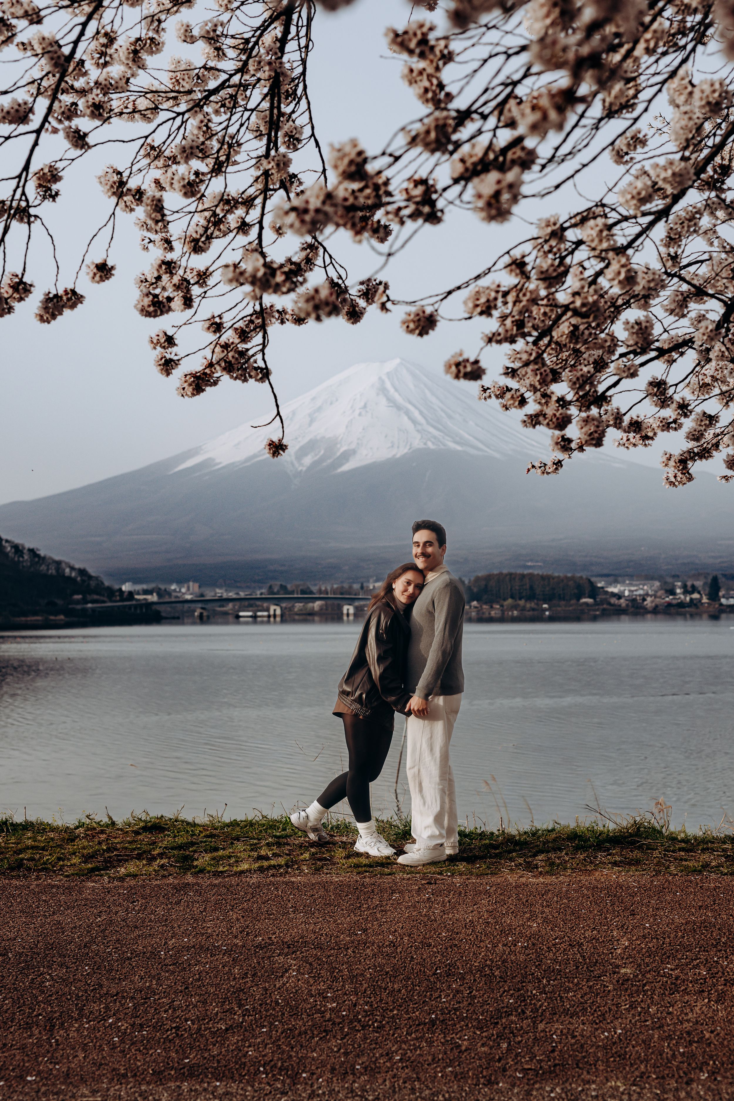 A scenic view of Mount Fuji with cherry blossoms framing the lake landscape during spring in Japan.