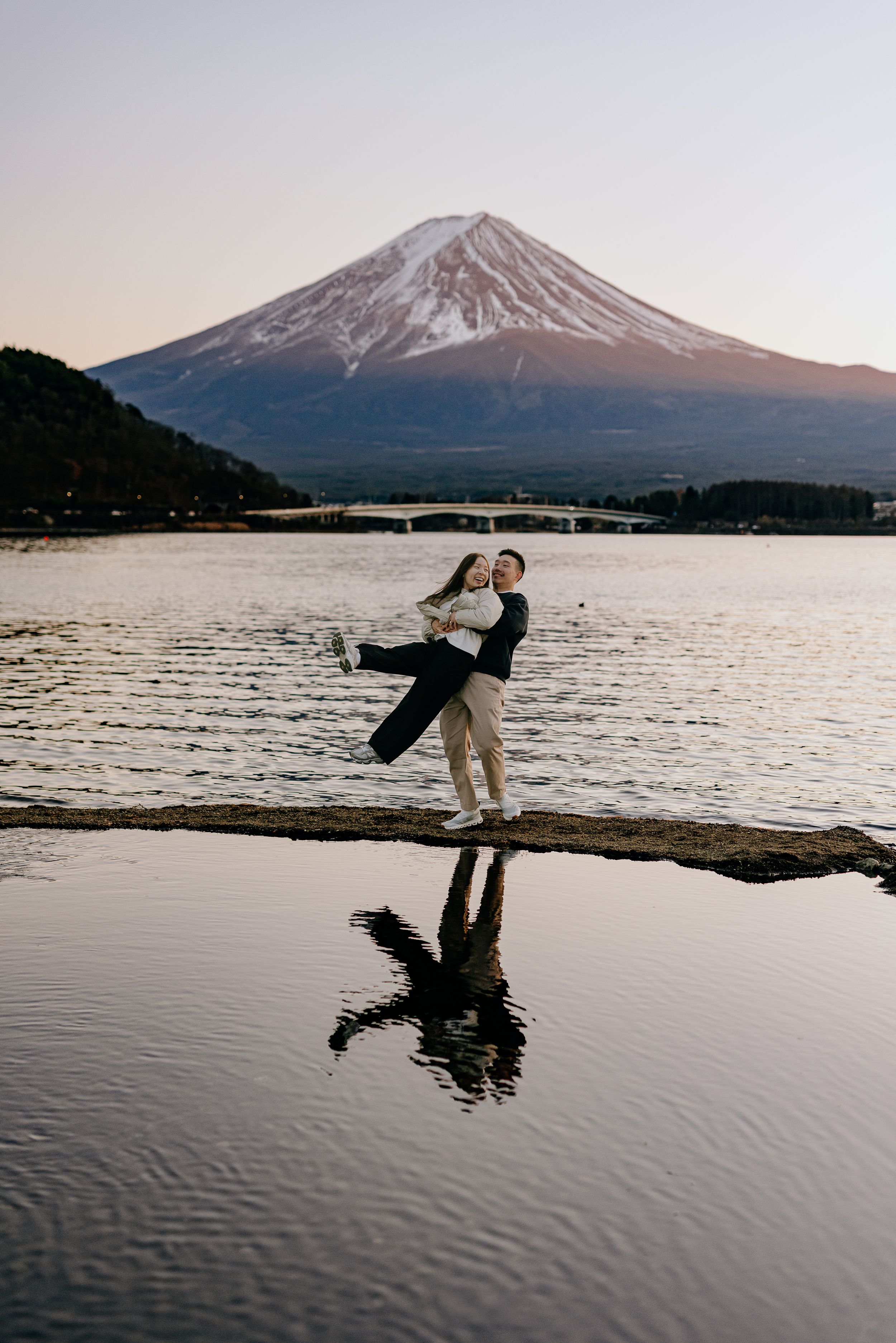 A sequence of silhouettes performing playful poses against Mount Fuji and Lake Kawaguchiko at sunset in Japan.