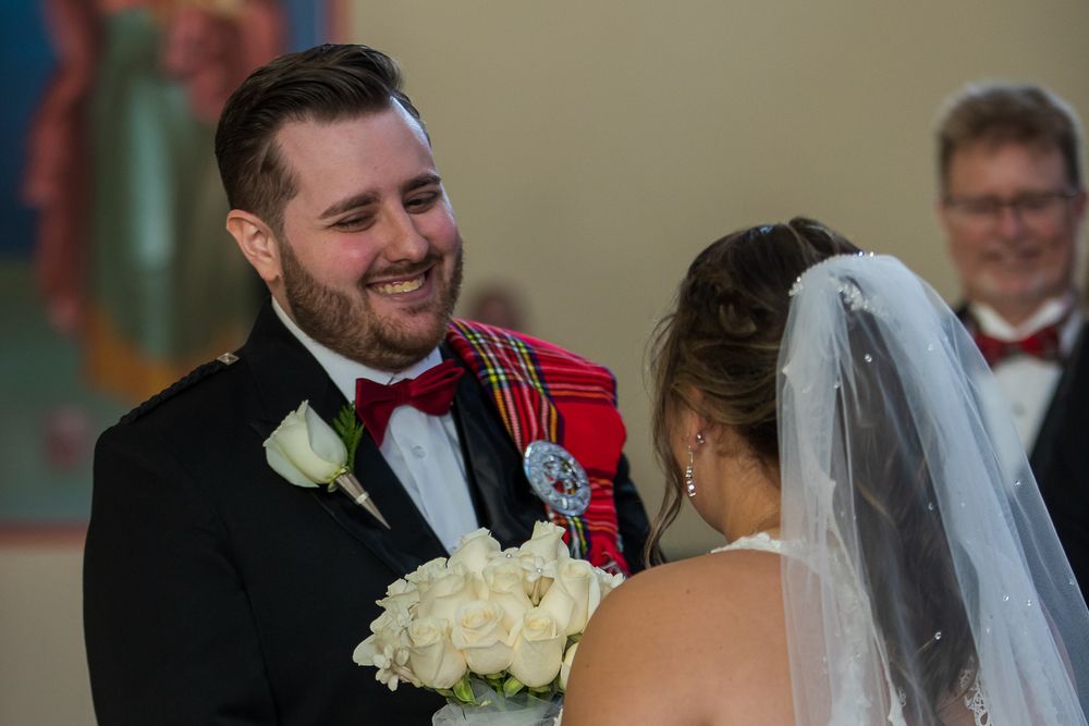 Wedding ceremony guests smile and celebrate during an indoor reception with formal attire.