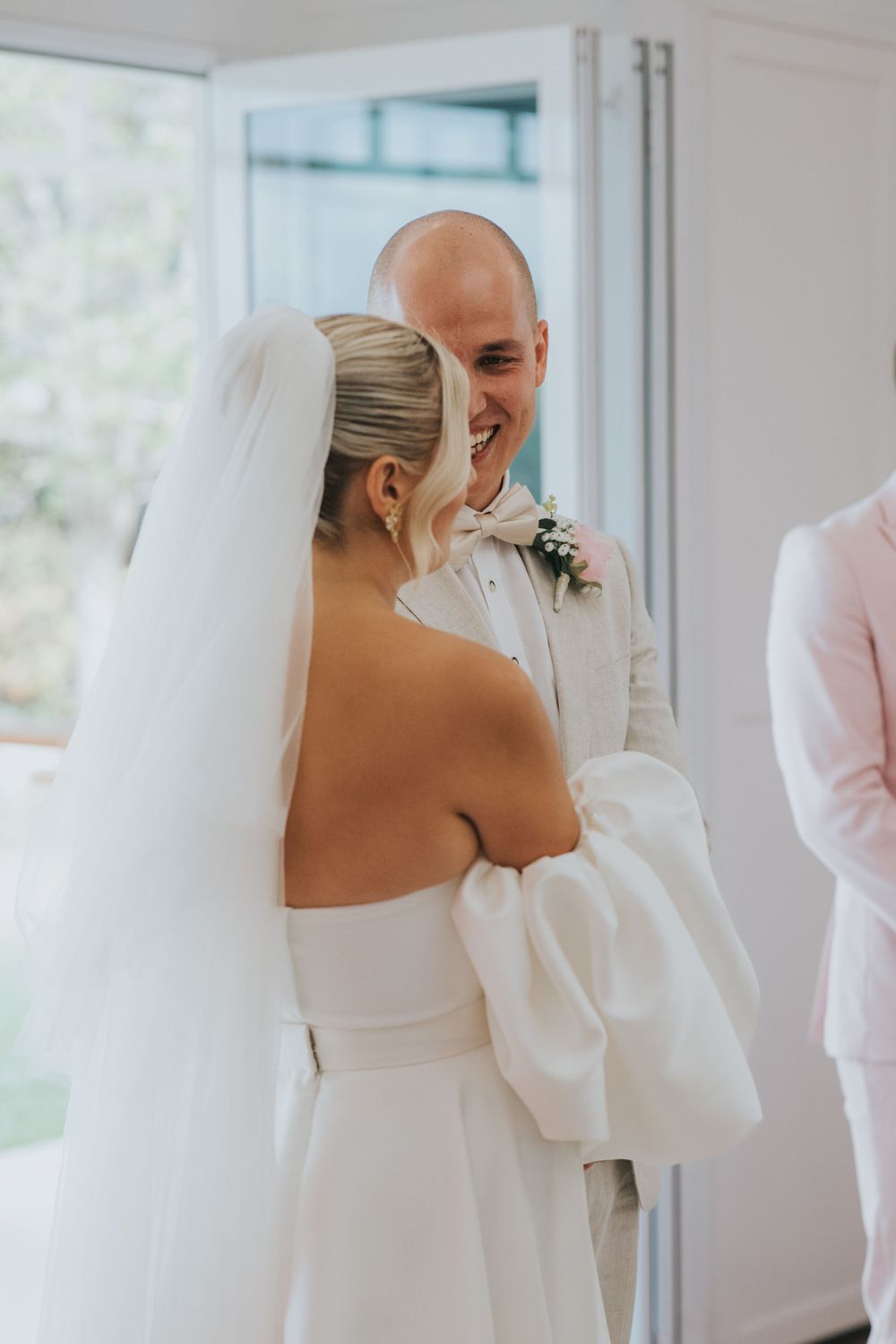 A tender moment captured during a wedding ceremony as a couple shares a joyful exchange in white attire.