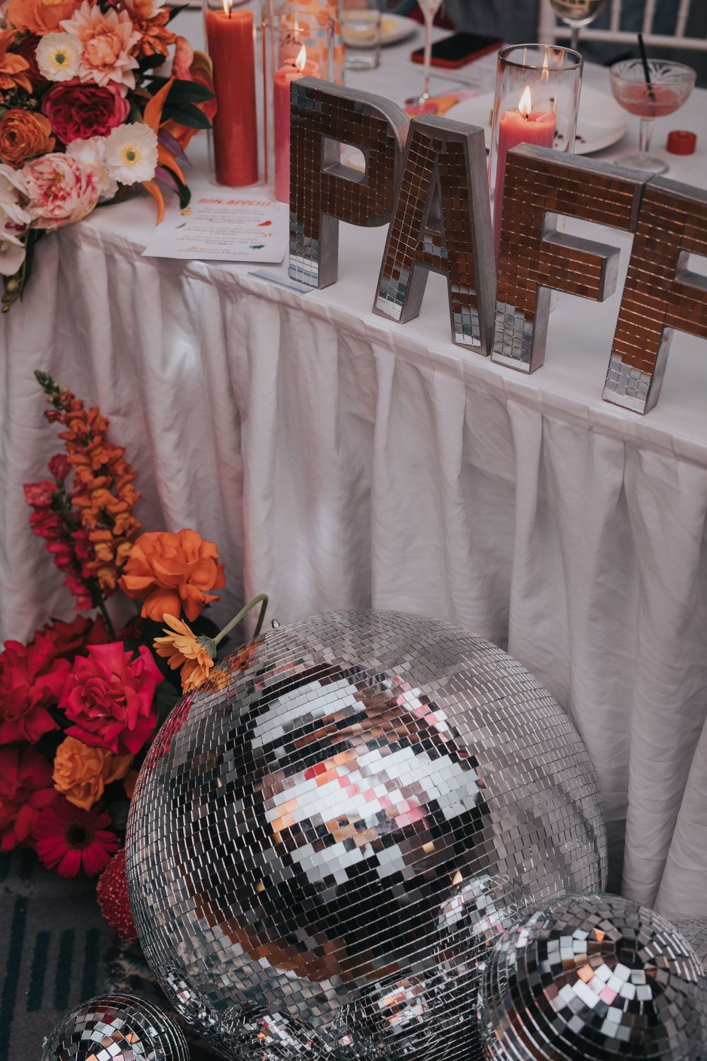 Disco ball decorations and colorful floral arrangements adorn a wedding reception table setting.