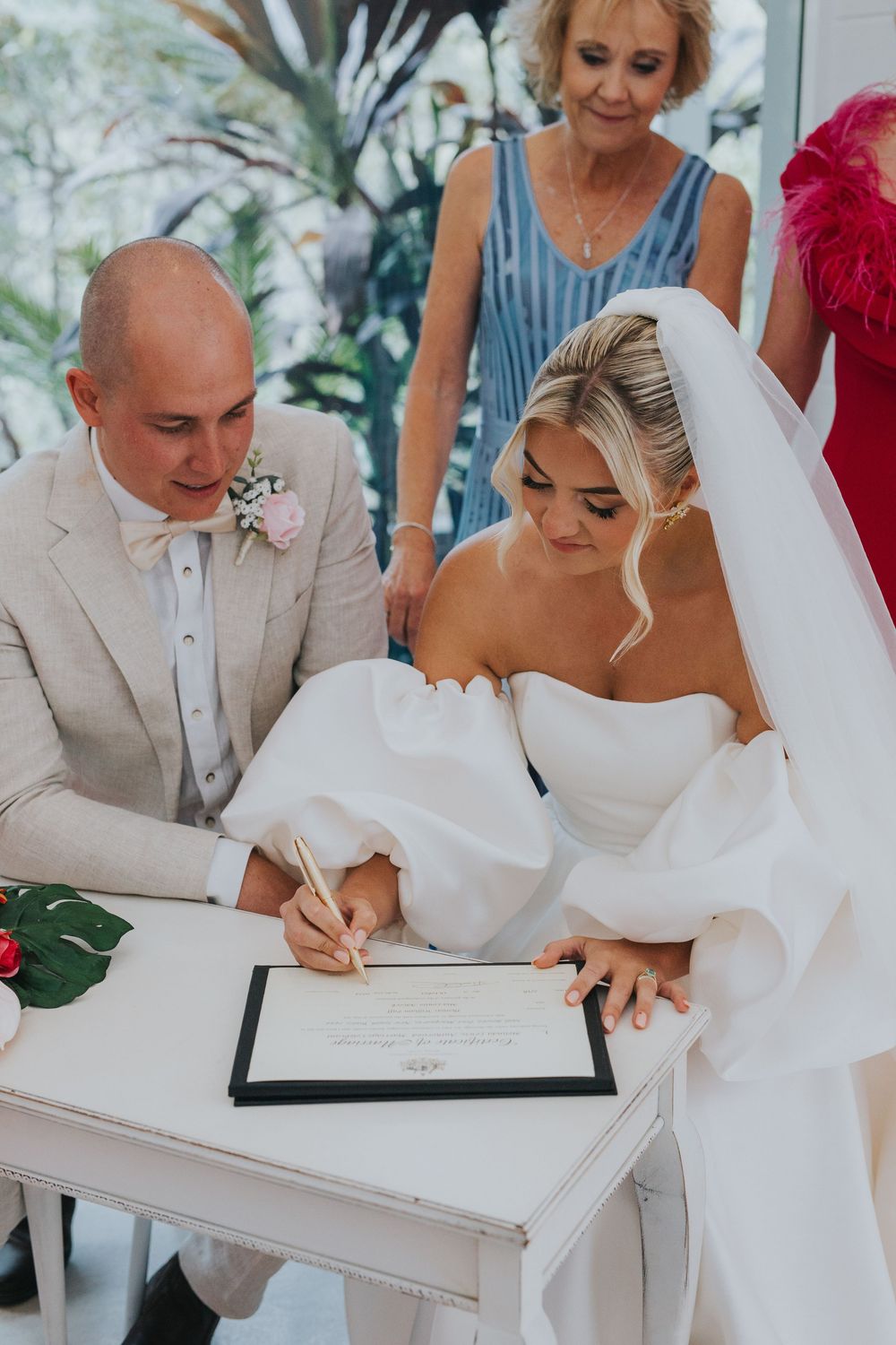 Wedding couple and guests signing official marriage documents at an elegant outdoor ceremony.