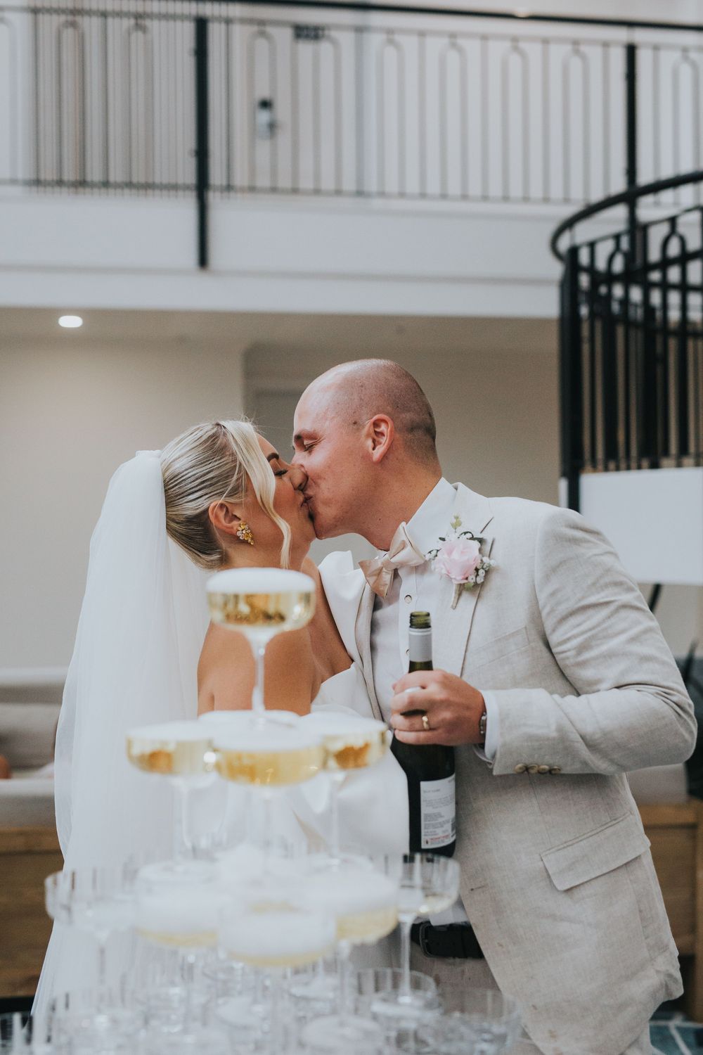 Newlyweds share a romantic kiss behind their elegant white and gold wedding cake during the reception.