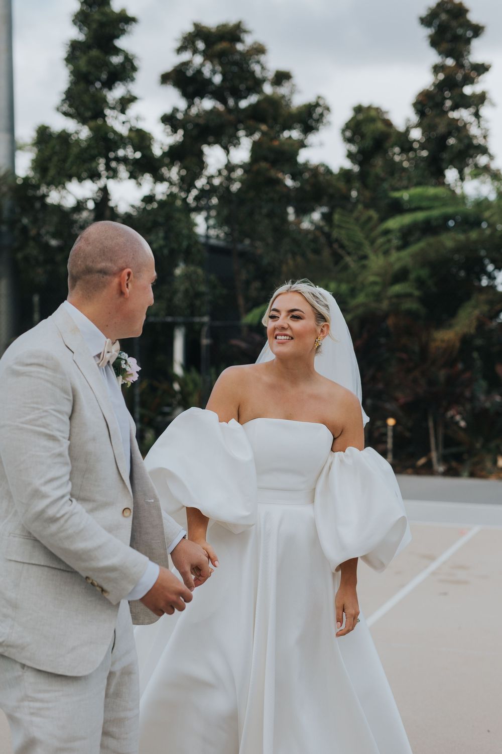 A couple shares joyful moments during their outdoor wedding ceremony with trees in the background.
