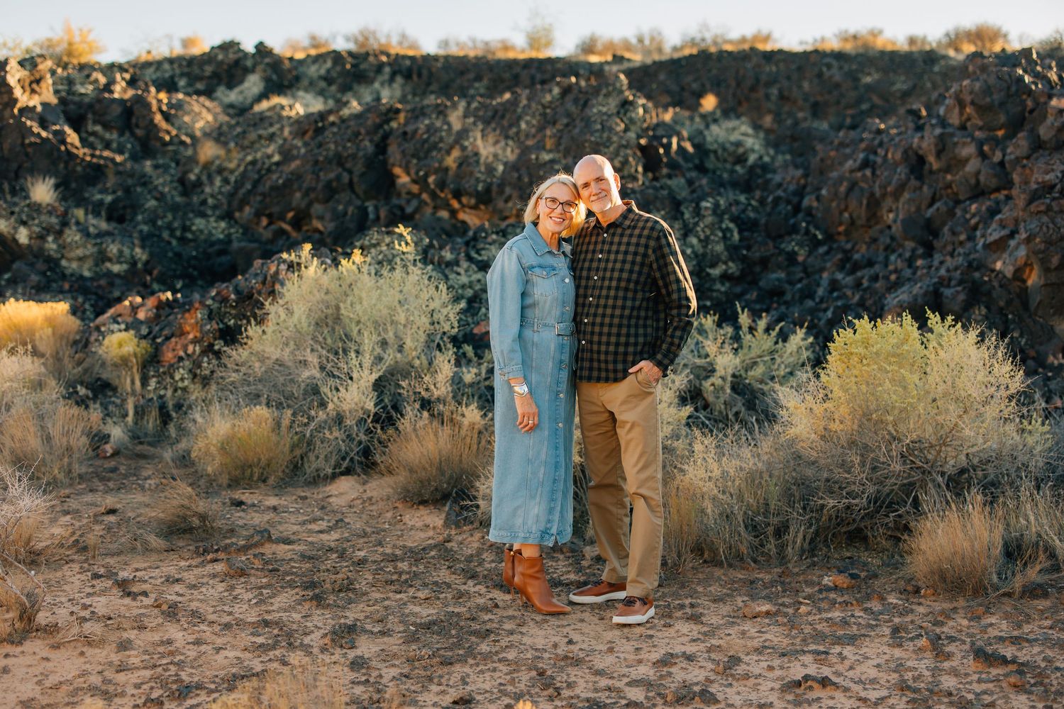 People walking through a golden field at sunset with mountains in the background.