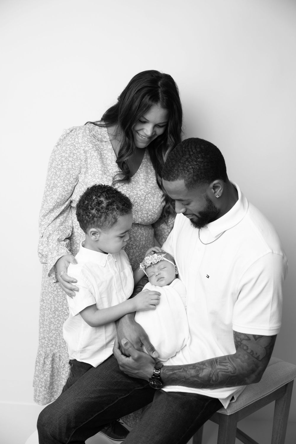 Black and white photo series showing tender family moments between parents and child in matching white outfits.