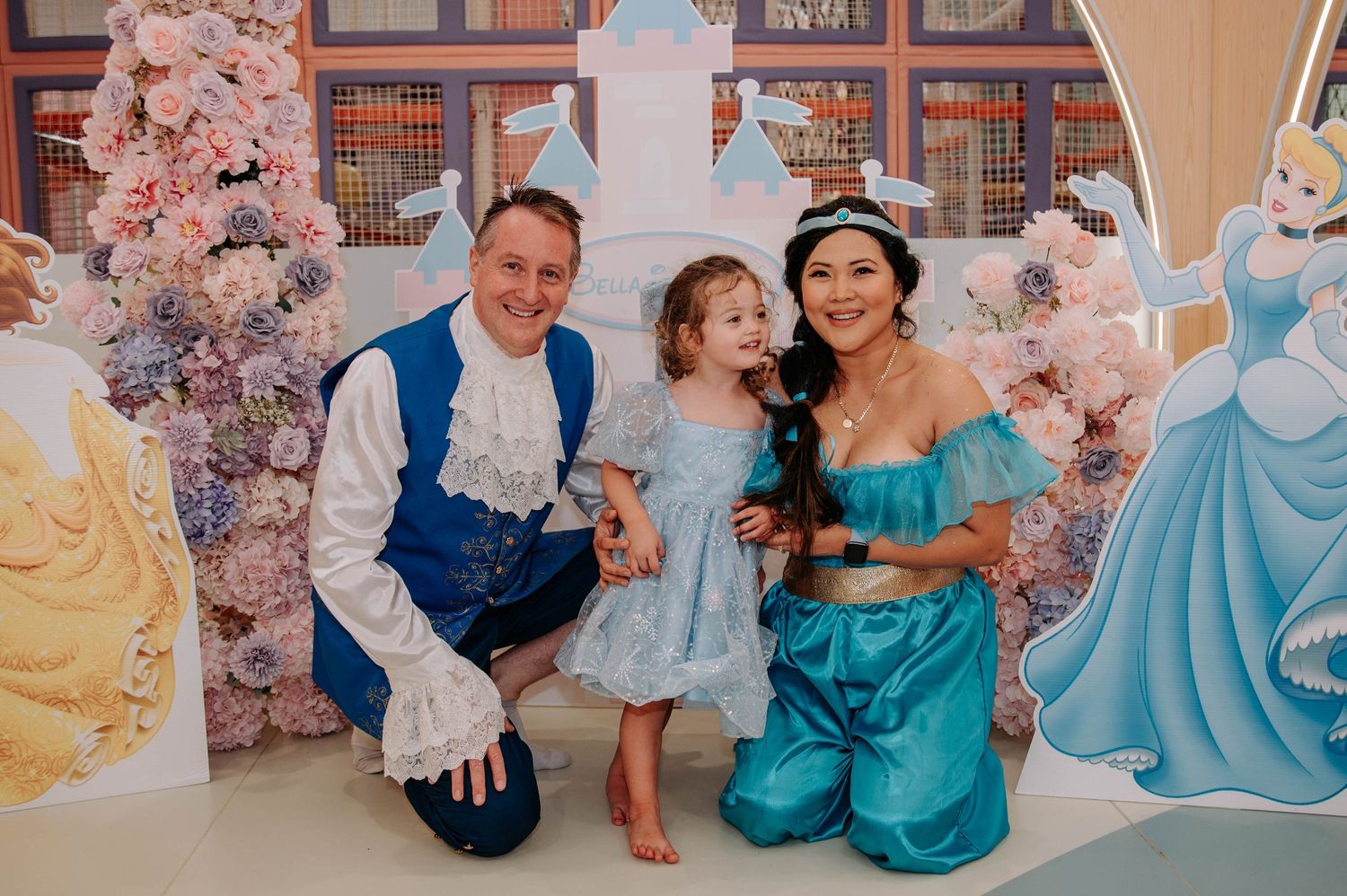 A princess-themed party setting with fantasy castle backdrop and pink floral decorations.