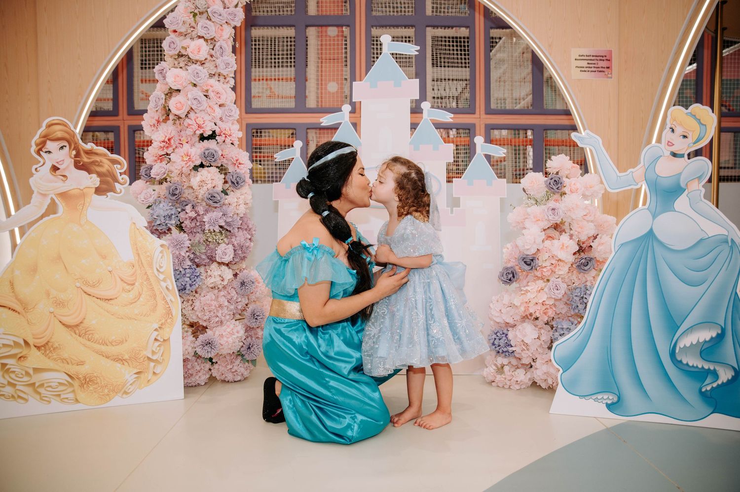A Disney princess themed photoshoot with pink floral decorations and character cutouts in the background.