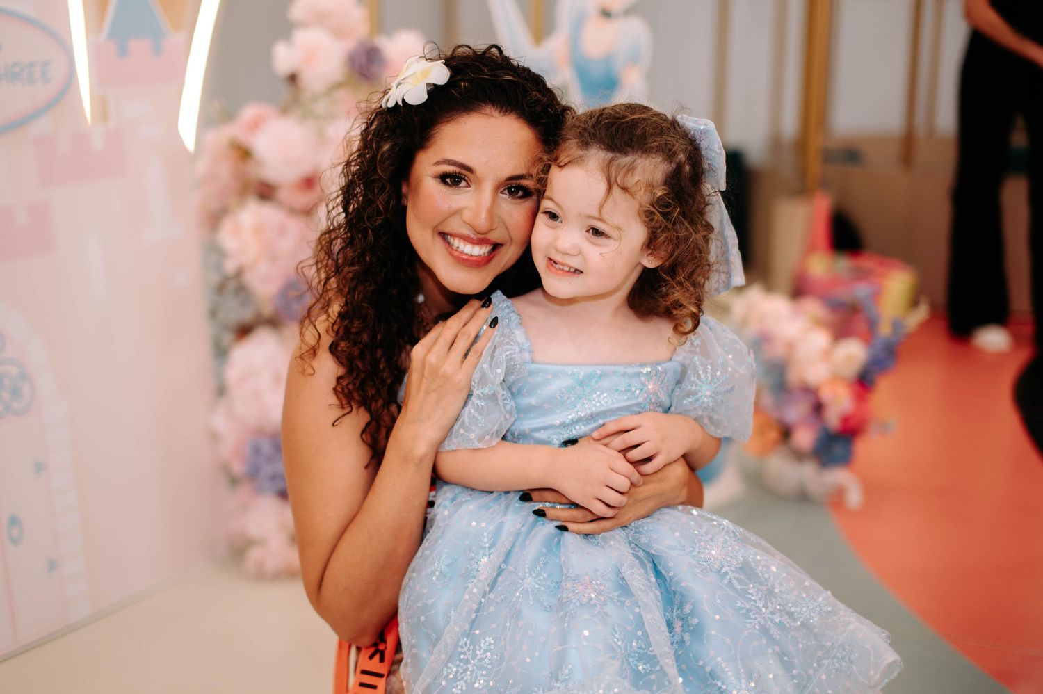 A heartwarming moment captured during a princess-themed celebration with decorative pink florals.