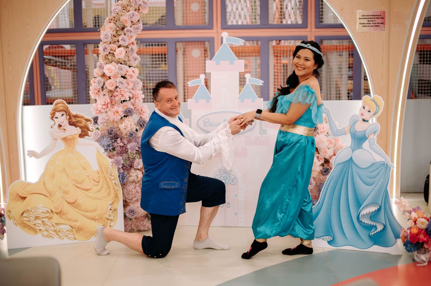 A playful photo session with performers in princess costumes against a Disney-themed backdrop.