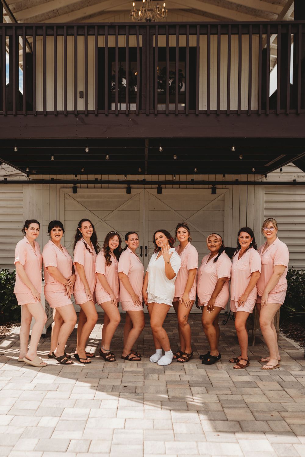 A group wearing matching pink outfits poses in front of a white barn-style building.