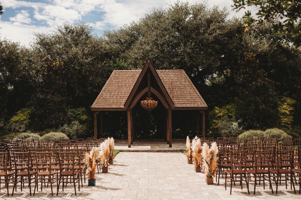 A wooden chapel with brown chairs lined up for an outdoor wedding ceremony.