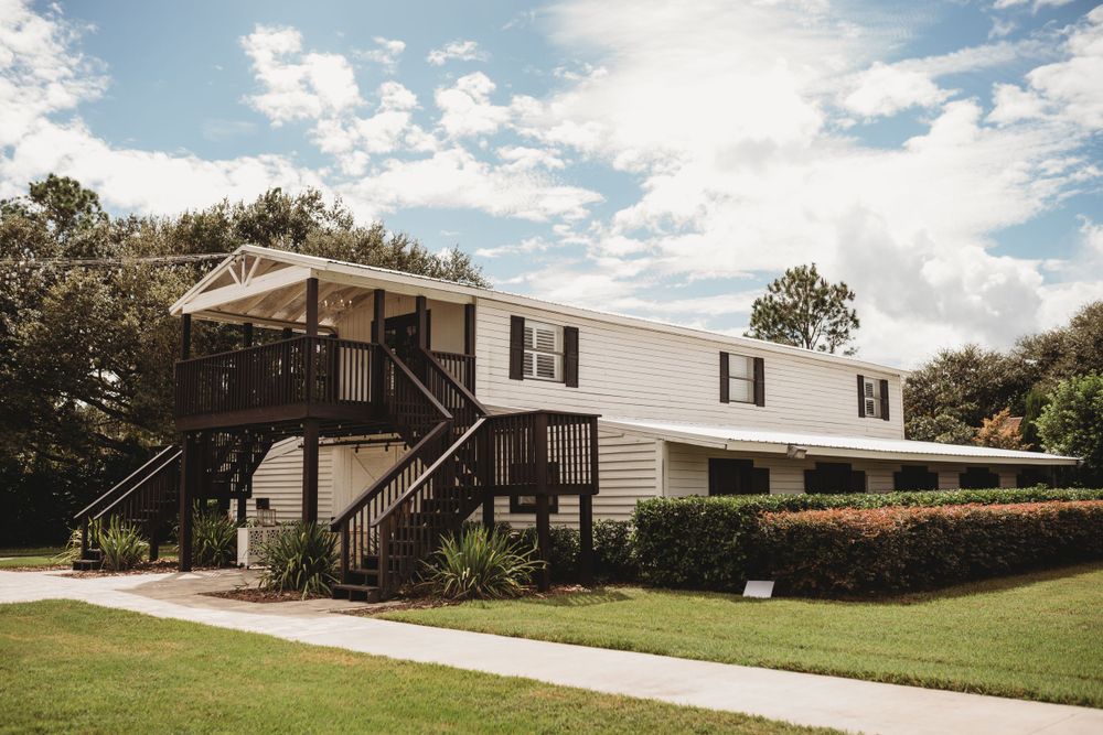 A white mobile home with dark trim and stairs leading to an elevated entrance.