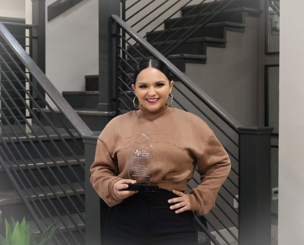 Portrait of a person wearing a brown sweater posing in front of modern stairs.