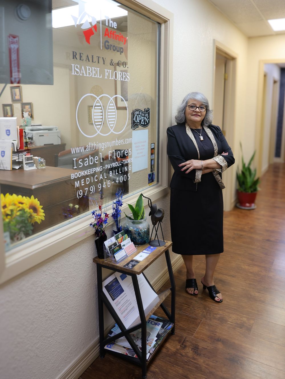 A professional stands in a business office hallway next to a branded window display.