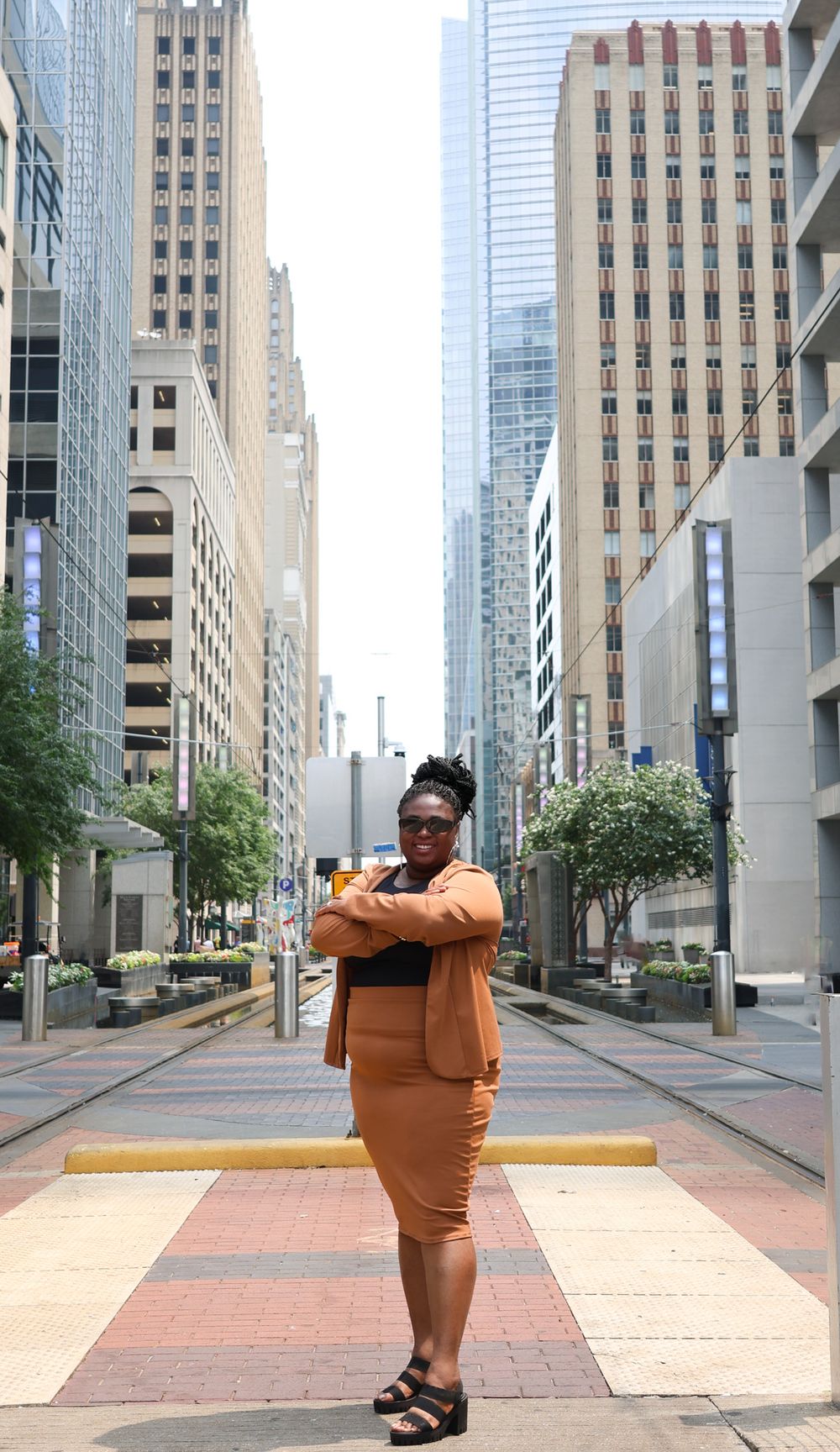 Urban photoshoot in downtown area with tall buildings and brick sidewalks.