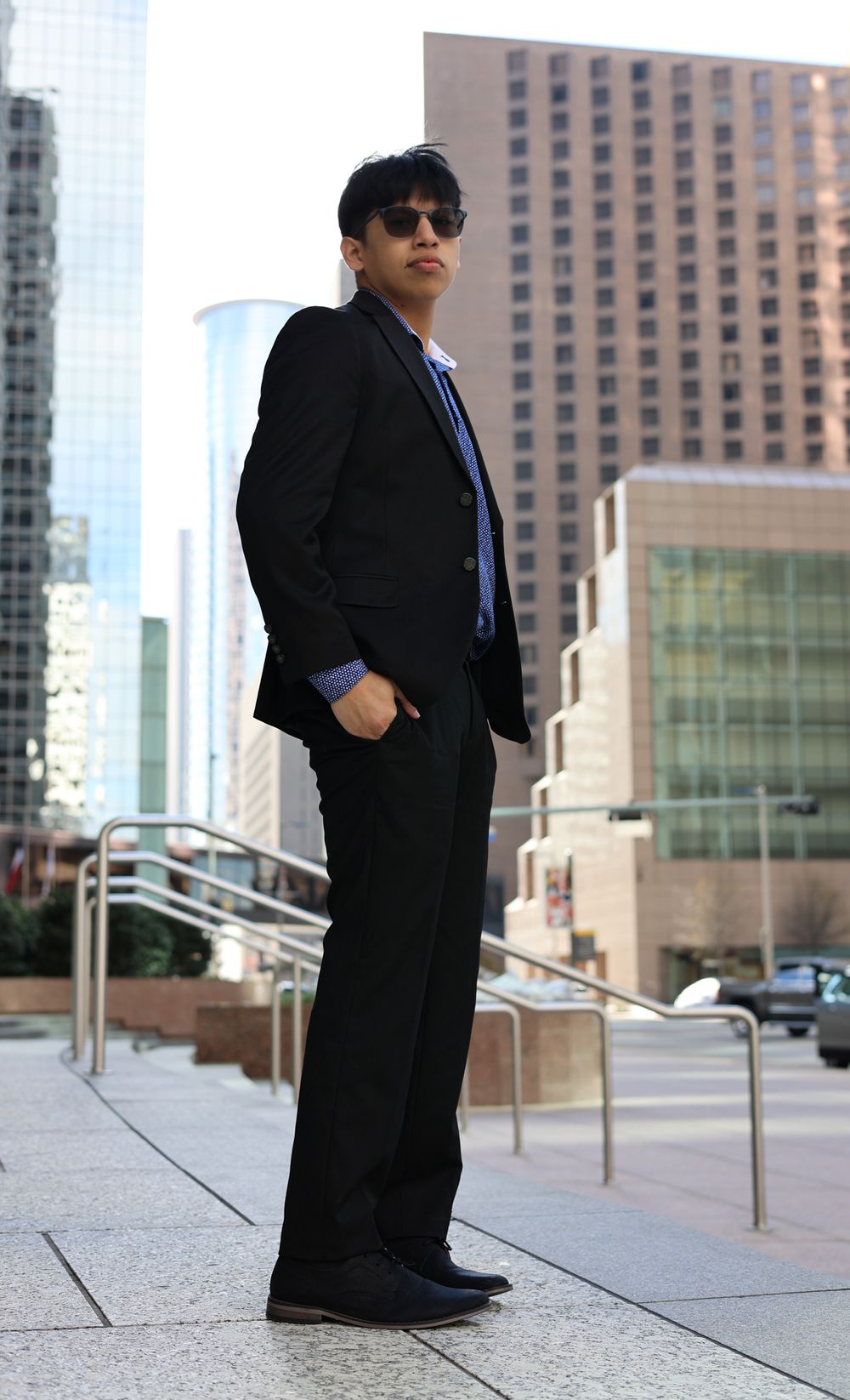 Professional photo series of a person in a black suit standing near modern office buildings and railings.