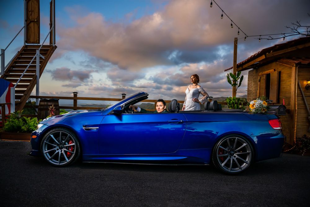 Bright blue BMW convertible parked at sunset with coastal view.