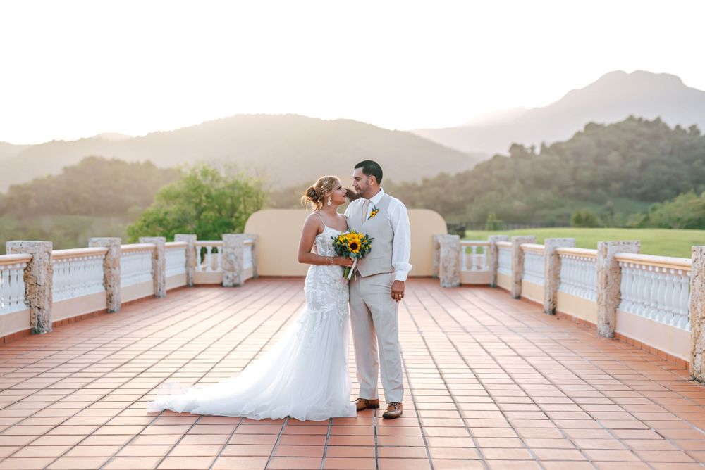 Wedding couple poses on Mediterranean style terrace with panoramic mountain backdrop.