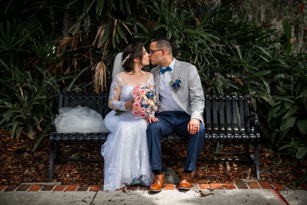 Intimate wedding portrait of couple sharing tender moment on garden bench.
