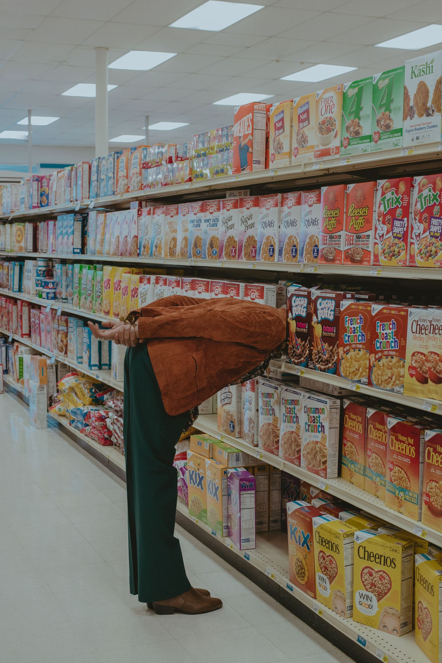 A portrait of a man in a suit posing on a cereal aisle in the grocery store.