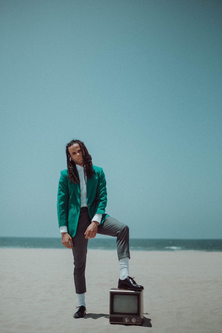 A portrait of a man standing on a tv at the beach.