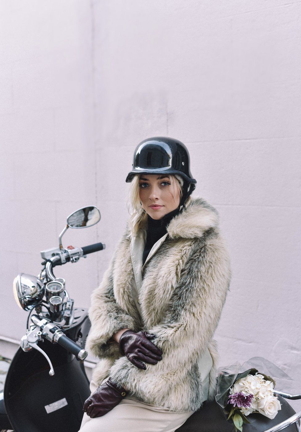 A portrait of a girl posing while sitting on a moped.