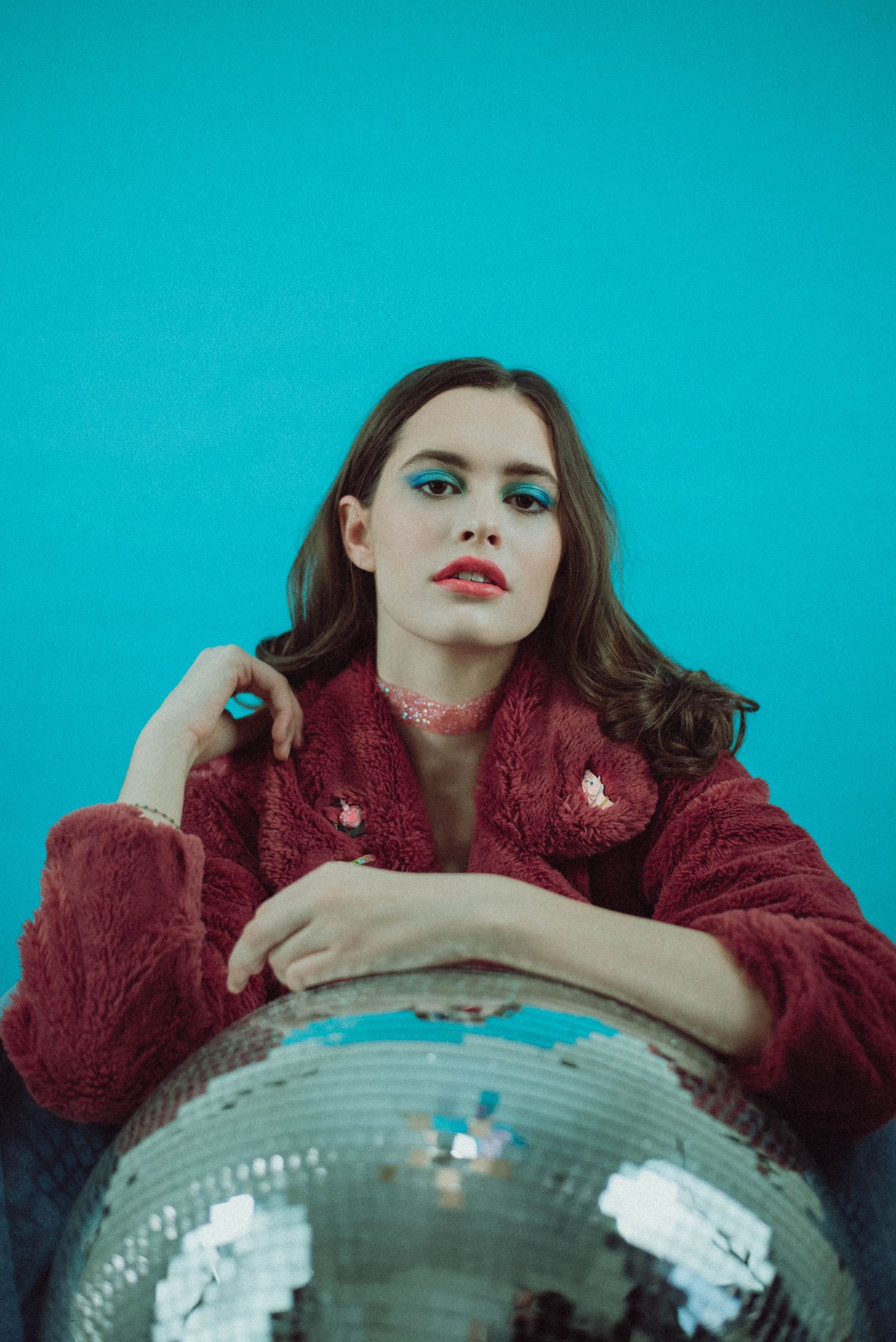A portrait of a girl posing while holding a disco ball.