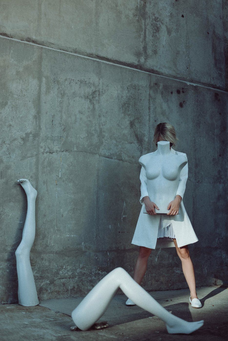 A portrait of a girl holding the top half of a mannequin while the other two mannequin legs are on the ground.