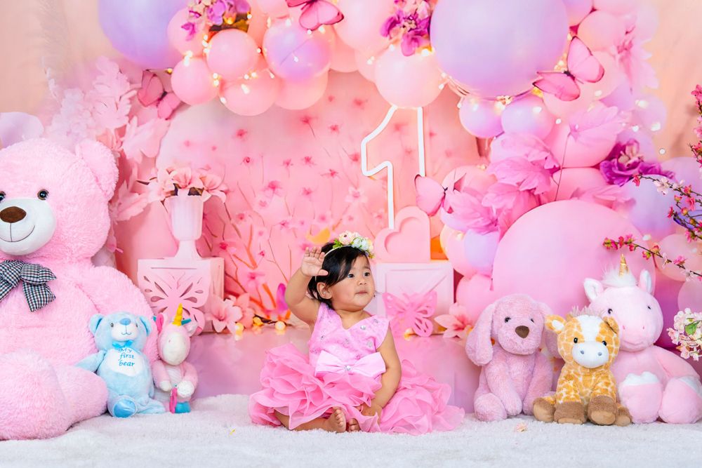 Pink birthday setup with stuffed animals and balloons creating a magical backdrop for a first birthday celebration.