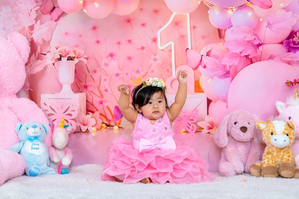 One year old celebration scene with pink balloons, teddy bears and decorative number one light.