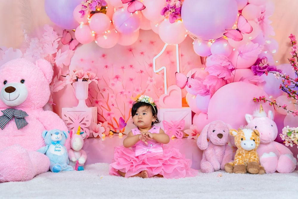Festive pink birthday setup with plush toys and balloons surrounding a celebratory scene.
