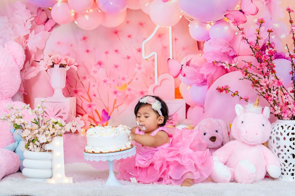 Pink themed first birthday celebration with cake, balloons, and stuffed animals creating a dreamy setting.