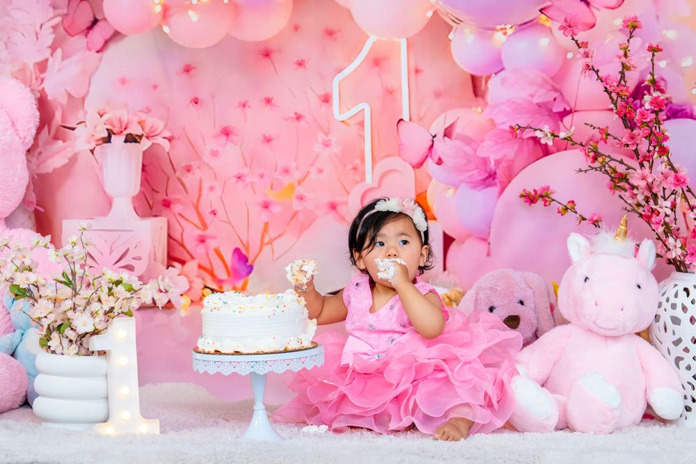 First birthday celebration with pink tulle dress, white cake, and festive balloon decorations.