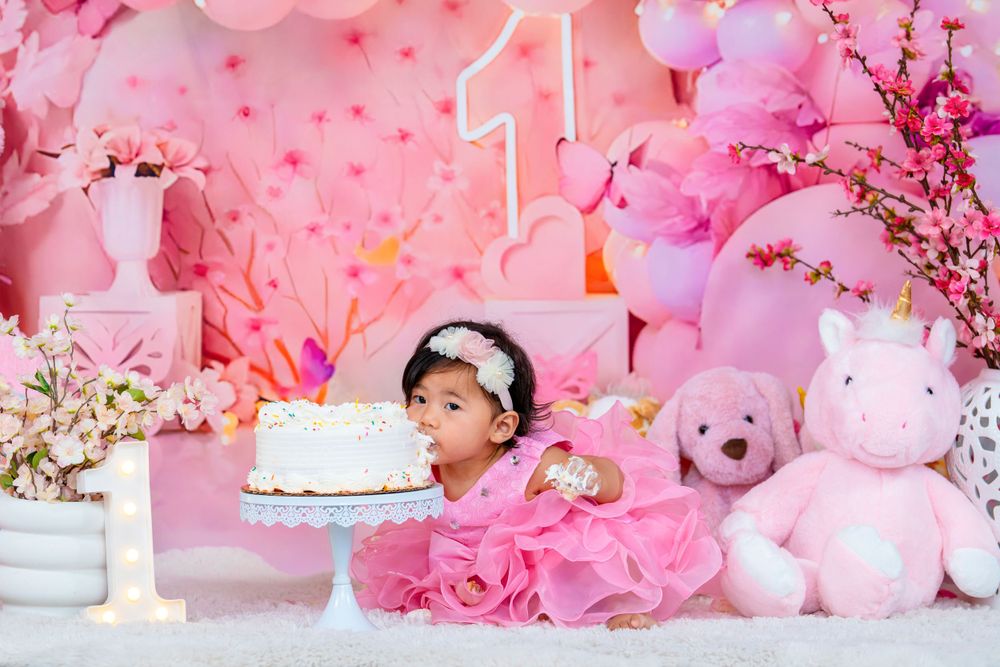 Pink and white birthday setup with cake and stuffed animals for a first year celebration.