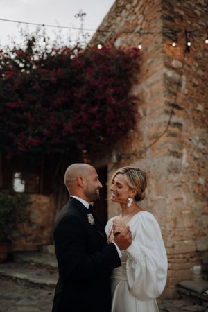 Bride and groom sharing a romantic moment outside a rustic stone wedding venue.