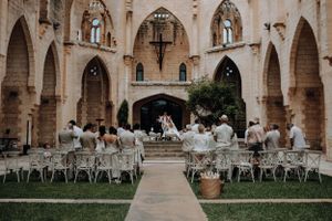 Guests seated at an outdoor wedding ceremony in a stunning stone archway venue.
