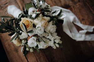 Romantic bridal bouquet of white and yellow roses on rustic wooden table.