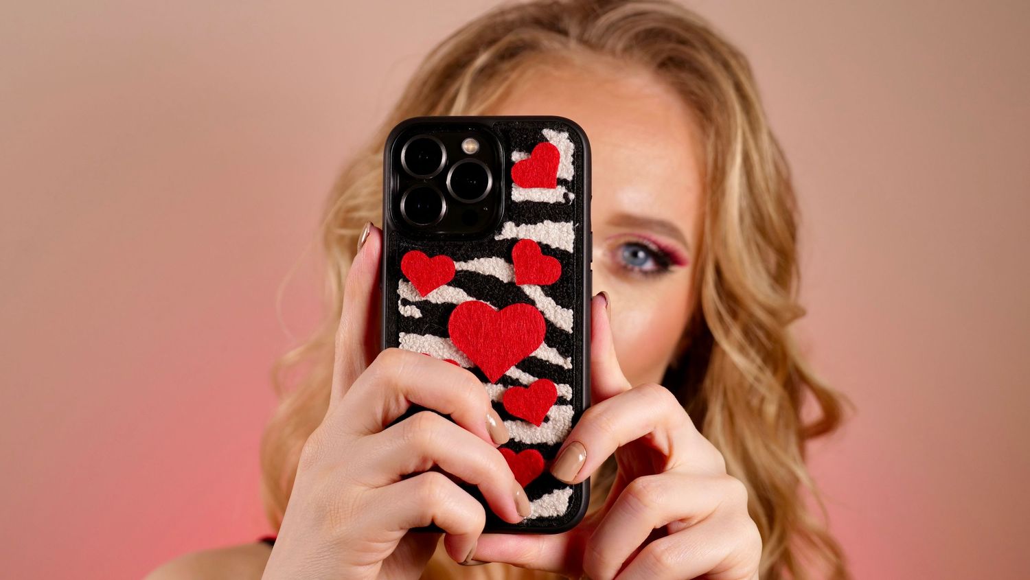 Person taking photo with smartphone in decorative red and black case.