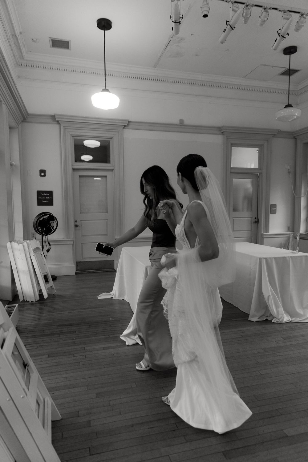 Black and white sequence of blurred dancers in a bright indoor studio with hardwood floors and white walls.