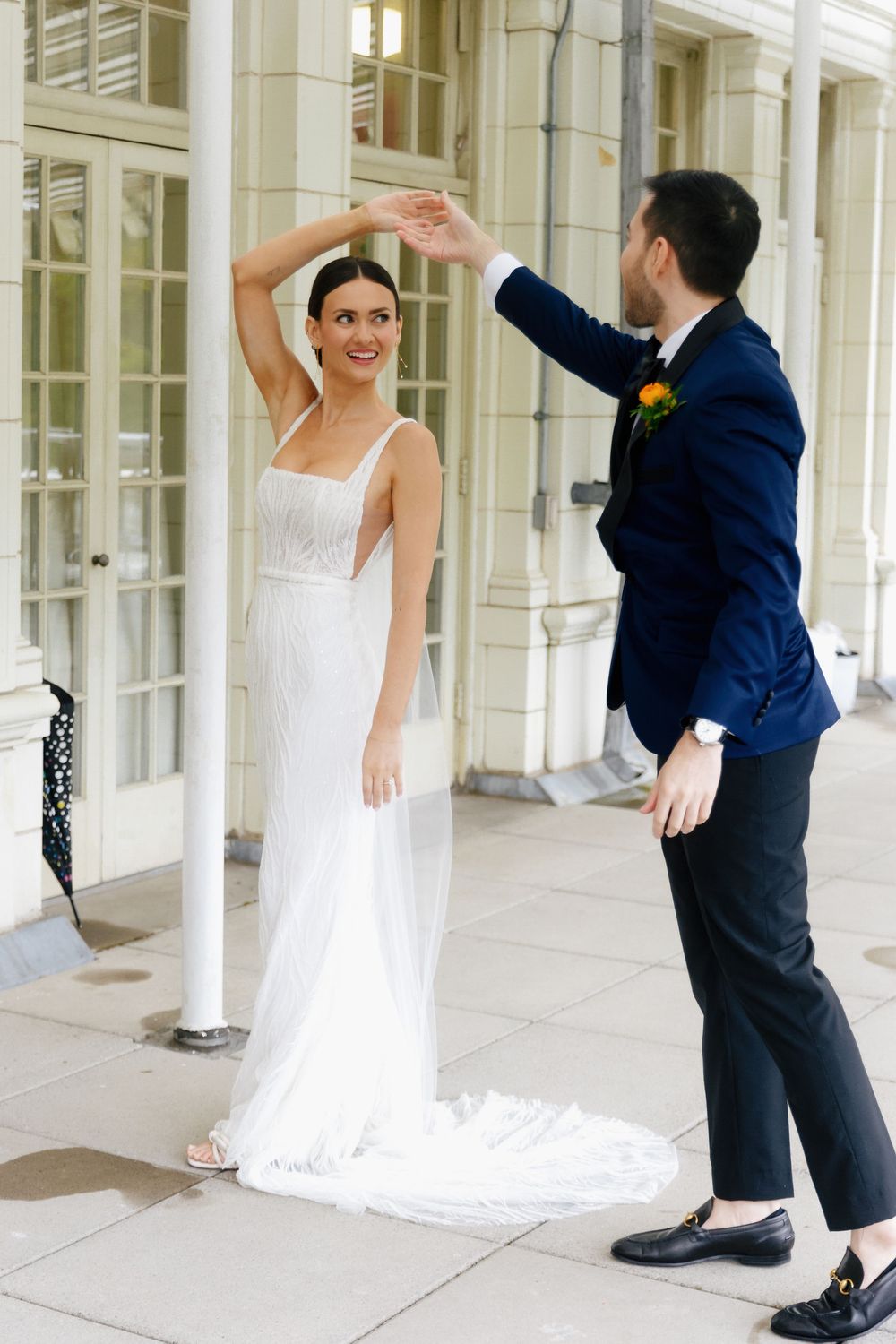 A couple dancing together on an elegant porch with white columns and French doors.