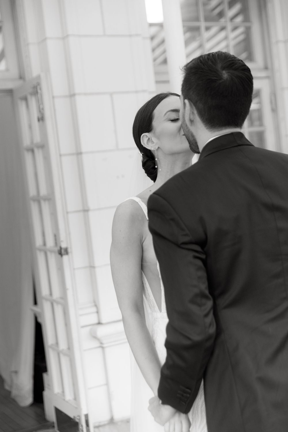 Intimate black and white wedding photos capturing couple's first look in hallway.