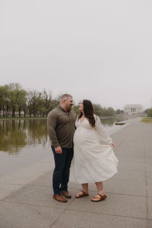 A couple shares a romantic moment near the Lincoln Memorial reflecting pool on a cloudy day in Washington DC.