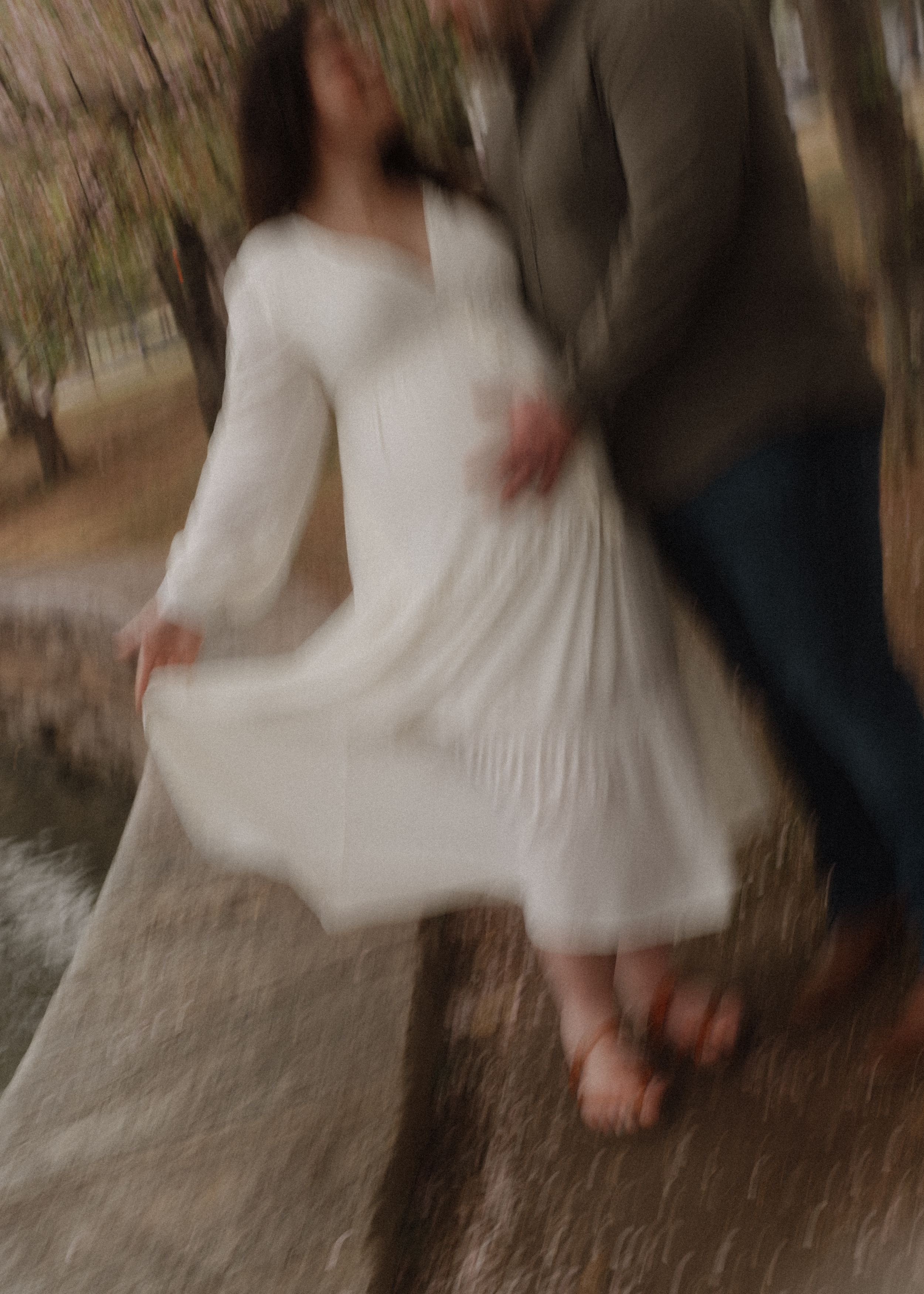 Motion-blur maternity photo of a couple dancing in casual attire outdoors.