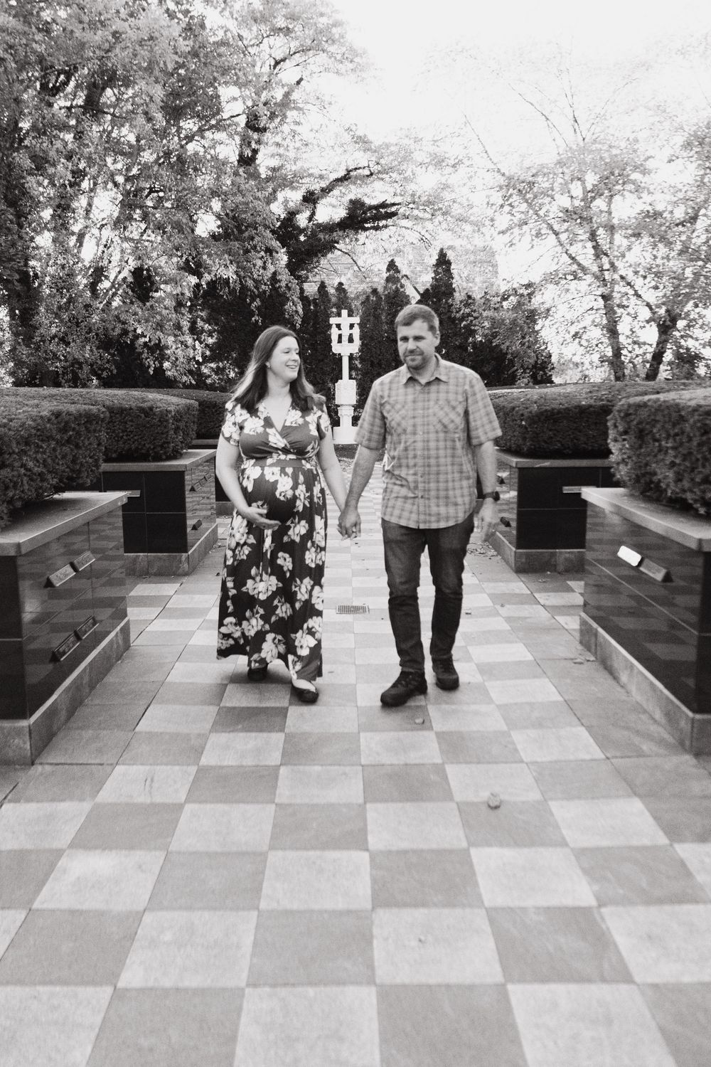 Couple walking together on a geometric patterned stone pathway in a garden setting during autumn.