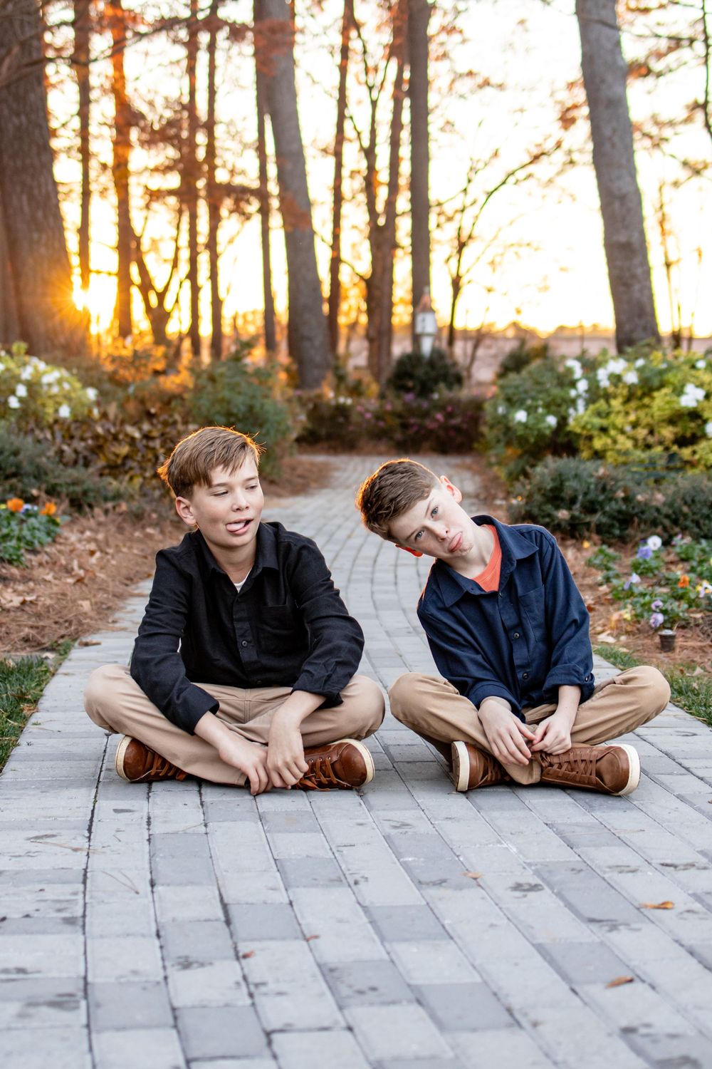 two brother sitting on a path in a garden
